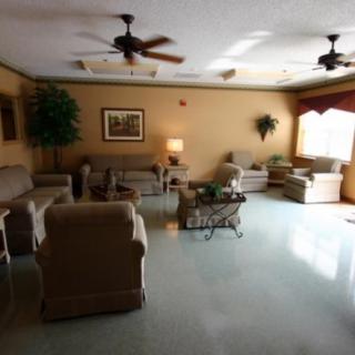 A cozy living room with sofas, chairs, a coffee table, and ceiling fans.