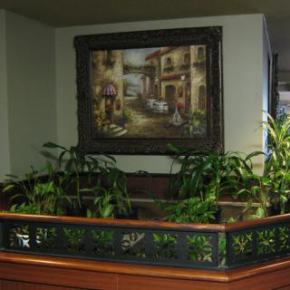 A cozy corner featuring a lush arrangement of plants beneath a decorative painting.
