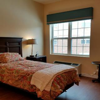 A cozy bedroom with a single bed, lamp, and window.