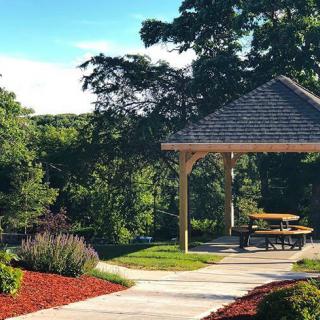 A serene outdoor picnic area with a gazebo surrounded by lush greenery.
