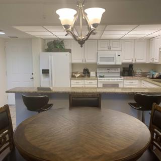 A cozy kitchen and dining area featuring a round wooden table, a chandelier, and white cabinetry with appliances.