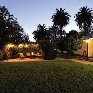 A tranquil garden with palm trees and cozy outdoor seating lit by warm evening lights.