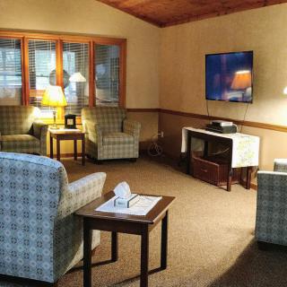 A cozy living room with plaid armchairs, a television, and warm lighting.