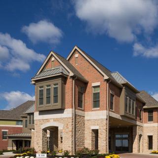 A modern suburban house with a brick facade under a partly cloudy sky.