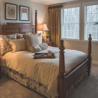 A cozy and well-decorated traditional bedroom with a wooden bed frame and soft lighting.