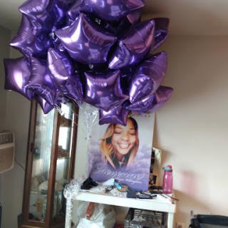 A vibrant display of purple balloons above a table featuring a poster.