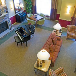A cozy living room with a grand piano, sofa, and fireplace.