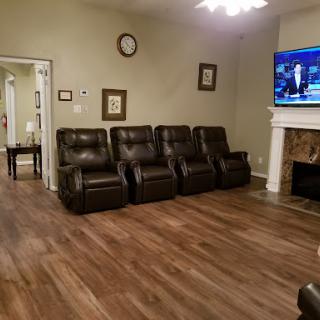 A cozy living room featuring black recliners, a television, and warm wood flooring.