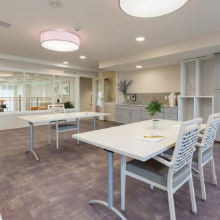 A modern conference room with tables, chairs, and bright lighting.