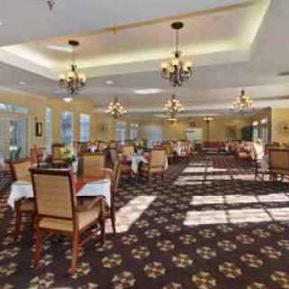 A spacious dining room with elegant chandeliers and neatly arranged tables and chairs.