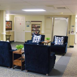 A cozy lobby seating area with dark chairs, decorative pillows, and small tables adorned with plants.