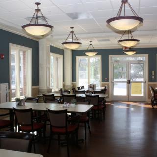 An empty dining area with neatly arranged tables and chairs under elegant lighting.