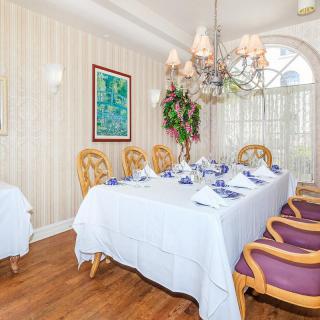 An elegantly decorated dining room with a large table set for a meal, surrounded by ornate chairs and illuminated by a chandelier.