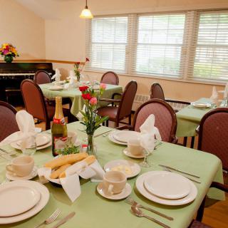 A well-set dining table in a cozy restaurant with green tablecloths and elegant decor.
