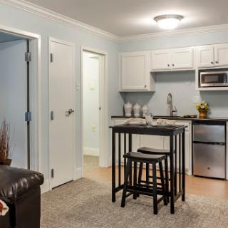 A cozy kitchen area in an apartment featuring a small dining table with stools and essential appliances.