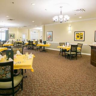 An elegantly set dining area with yellow tablecloths and ample lighting.