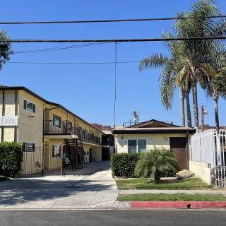 A sunny view of an apartment complex with palm trees lining the property.