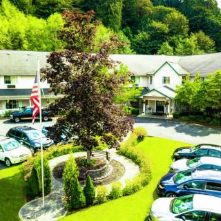 A scenic view of a building with well-maintained landscaping, surrounded by parked cars and lush greenery.