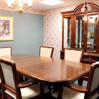 A cozy dining room featuring a large wooden table surrounded by upholstered chairs, complemented by elegant lighting and tasteful wall decor.