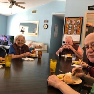 A group of elderly individuals enjoying a meal together around a dining table.