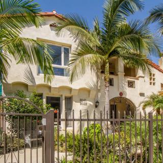 A tropical-style house with palm trees and a gated entrance.