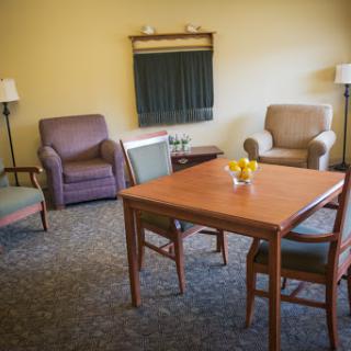 A cozy living room area featuring comfortable chairs and a wooden dining table.