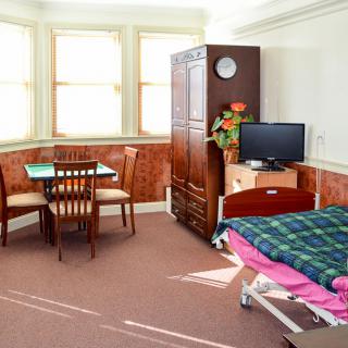 A cozy room with a bed, a small dining table, and a television.