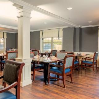 A spacious dining room with neatly arranged tables and chairs on a hardwood floor.