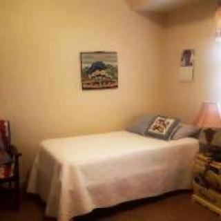 A cozy bedroom with a neatly made bed, a lamp on the bedside table, and artwork on the wall.