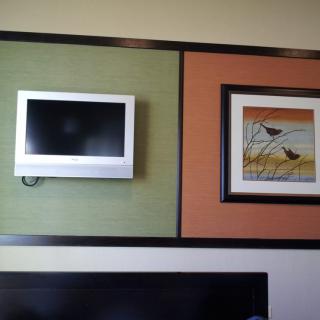 A small television and a framed artwork mounted on a color-blocked wall.