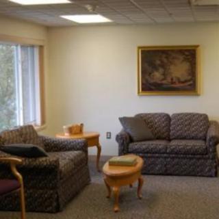 A cozy waiting room with sofas, a coffee table, and a wall painting.