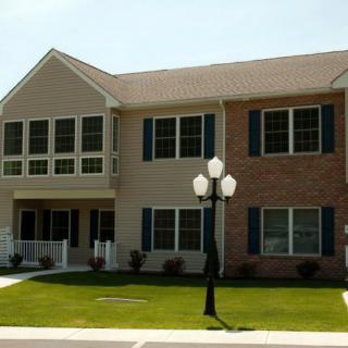 A suburban duplex with a brick facade and a well-maintained lawn.