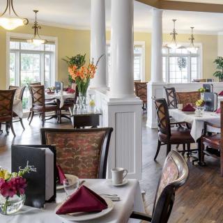 An elegant dining room with neatly arranged tables and chairs, featuring floral decor and ambient lighting.