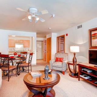 A cozy living room with comfortable seating, a coffee table, and a dining area in the background.