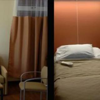 A hospital room with a bed, curtain, and chair.