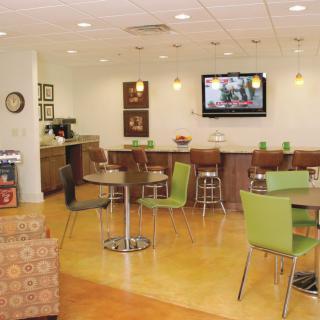 A cozy cafe interior with tables, chairs, a television, and modern lighting.