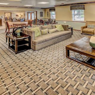 A cozy living room with patterned carpet, comfortable seating, and tasteful decor.