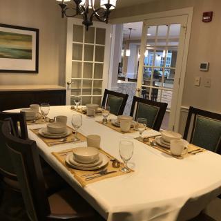 A dining room with a table set for a meal, featuring plates, glasses, and a chandelier.