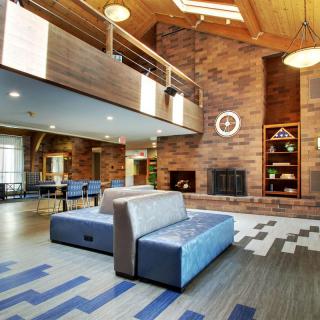 A modern lobby with stylish furniture and a large fireplace.
