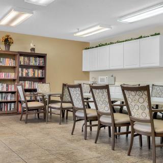 A well-organized meeting room with a large table, several chairs, and a bookshelf filled with books.