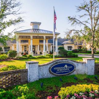 A beautiful building with a grand entrance surrounded by well-maintained gardens and flags.