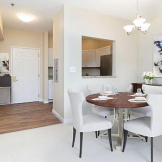 Modern dining area with a round table, elegant chairs, and an open kitchen in the background.