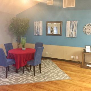 A cozy dining area with a red tablecloth, blue chairs, and various decorative elements.