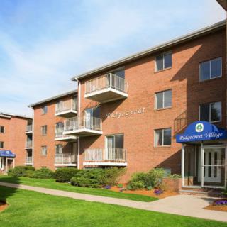 A brick apartment building with balconies and landscaped grounds.