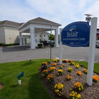 Entrance to a facility with a landscaped garden and signage.