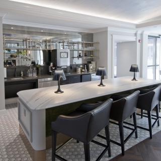 A modern kitchen interior featuring a sleek countertop with bar stools and contemporary lighting.