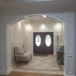 A cozy foyer featuring elegant double doors, a seating area, and soft lighting.