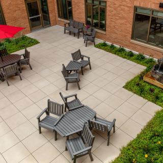 An outdoor courtyard with tables and chairs set up on a patio next to a brick building.