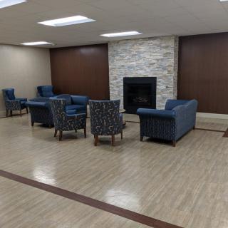 A modern lounge area with sofas and chairs arranged around a fireplace.