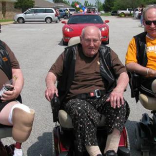 Three men in wheelchairs on a street.